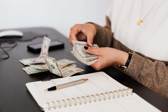 crop-payroll-clerk-counting-money-while-sitting-at-table.jpg
